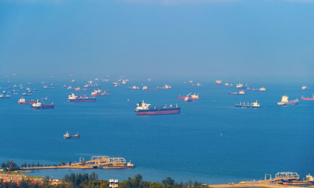 Cargo tanker ships in transportation concept. Shipping boats at Singapore harbor with blue sky at noon. Clear blue sea.